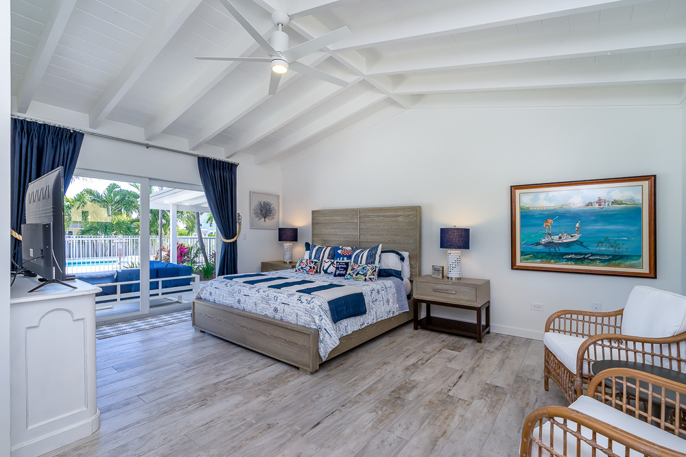 King master bedroom suite with seating, TV, and private access to patio overlooking the private pool at marathon Florida vacation rental