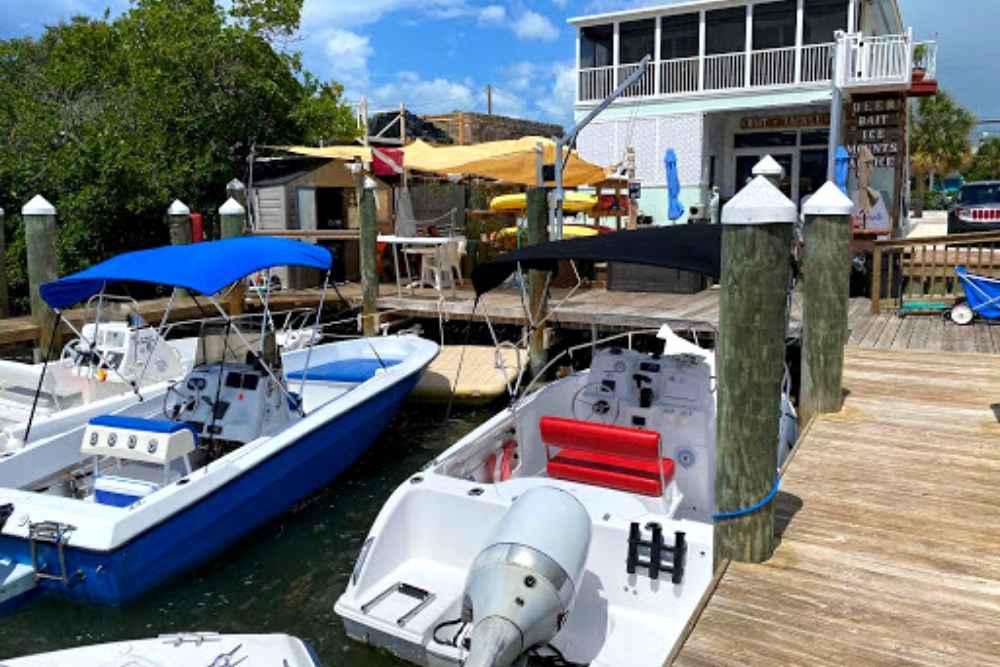 2 boats tied up at the dock in front of a boat rental shop in marathon, florida