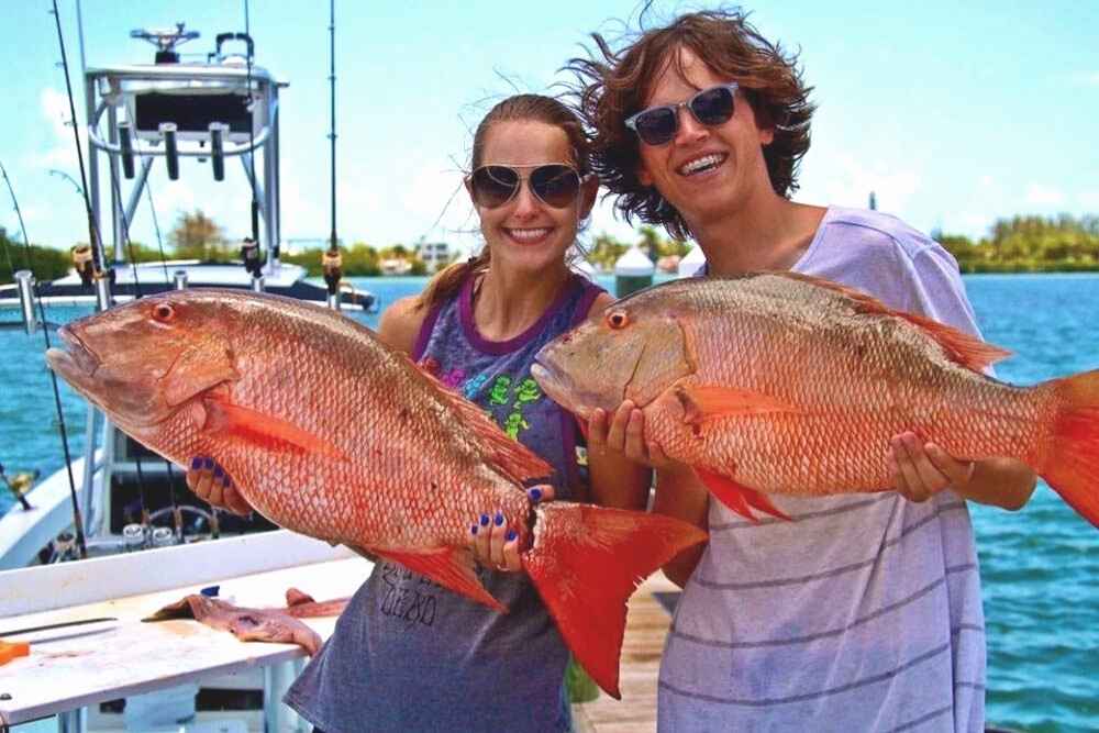 Woman and Man couple each holding a red snapper fish in the Florida Keys