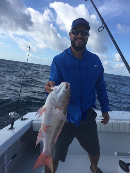 Man holding a fresh caught grouper fish while on a boat the Florida Keys