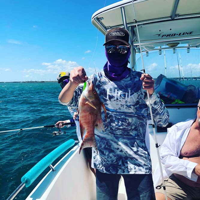 Young man holding his hogfish catch and rod while on a boat in the Florida Keys